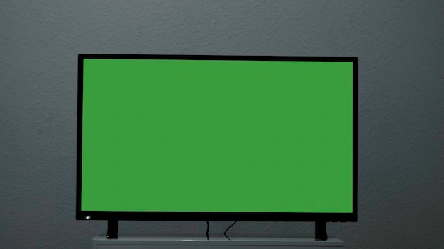 Photo plasma tv with green screen stands on background wall concept greenscreen tv stands on background