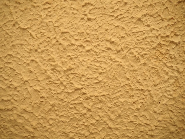 Plaster finishing layer formed by hardened building cement mortar Handplastered wallsa with the effect of waves elevations and irregularities Yelloworange abstract background