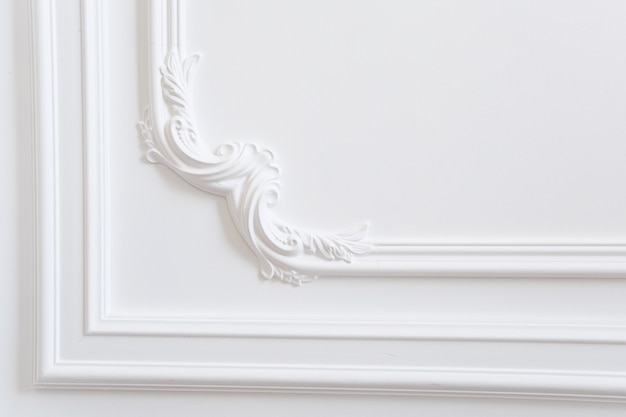 Фото Гипсовая лепнина - это декоративное украшение белой стены в классическом стиле.