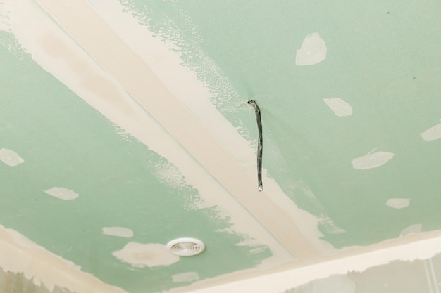 Plasterboard ceiling with electricity cable wires and ventilation in unfinished bathroom Construction of house and home renovation concept Close up of dropped ceiling