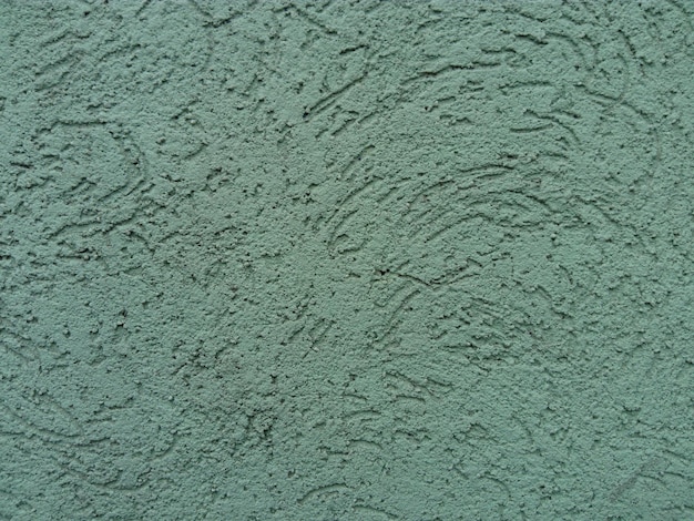 緑の壁を漆喰で仕上げる モルタルを硬化させて仕上げ層を形成する へらでセメントのテクスチャーを塗る インテリアに化粧しっくいを使用するのが一般的になりつつある