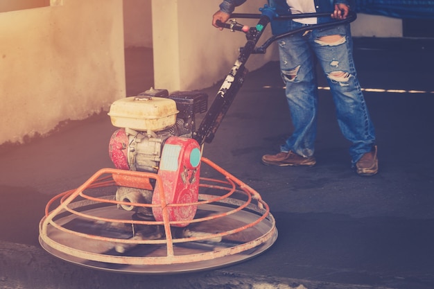 Foto impresa di stuccatura che lavora con macchina di lavaggio per pavimento in cemento con annata tonica