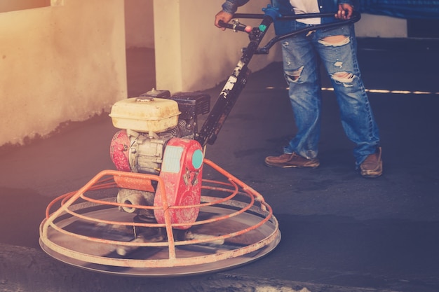 セメント床用スクラバーマシンを使用していて、ヴィンテージトーンで作業しているPlasterer