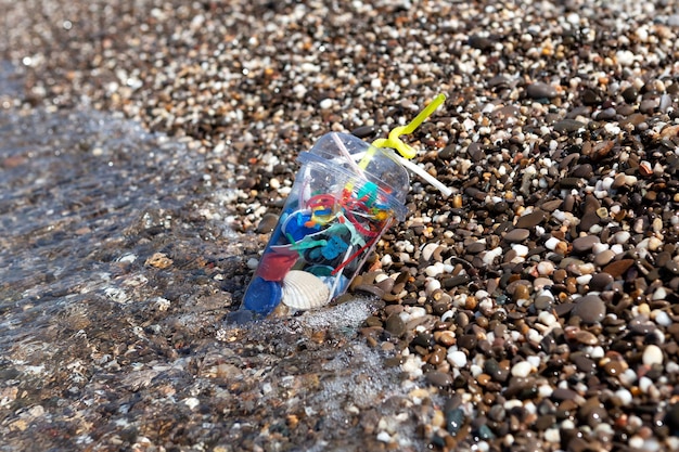 Plastic afval op zeestrand Plastic wegwerpbeker Vervuiling van huishoudelijk afval in het watergebied