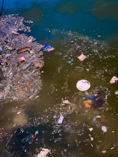 Plastic afval zwemt op het wateroppervlak Vuilnis bij vuil water