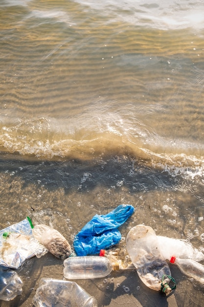 Полиэтиленовый пакет и бутылки на концепции загрязнения пляжа, seashore и воды.