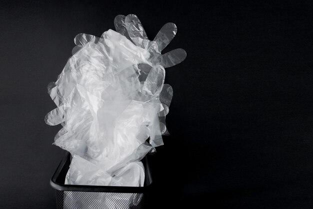 plastic bag with handles gloves in the bin on a black background used plastic bag for recycling concept ecology planet pollution with plastic cellophane polyethylene