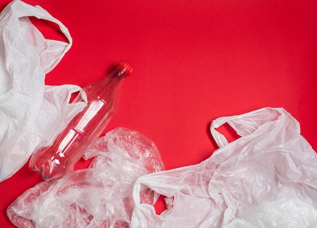 Plastic bags and bottles on a red background with space for textxaecology mockup