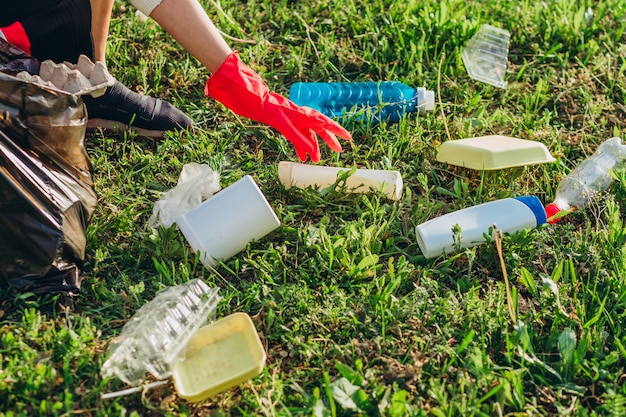 Plastic bags dumped in the meadow contaminate environment. Pile plastic and glass bottles on green grass in the nature environment problems. Nature protection.