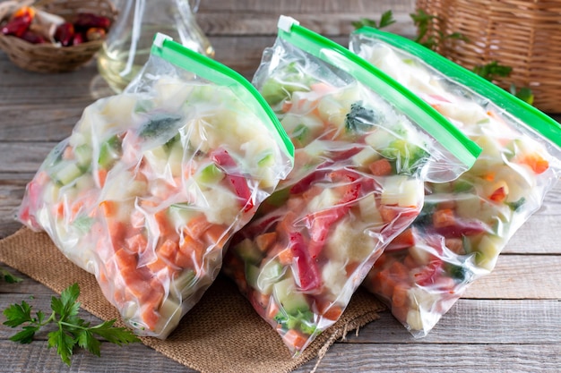 Plastic bags with different frozen vegetables on wooden table