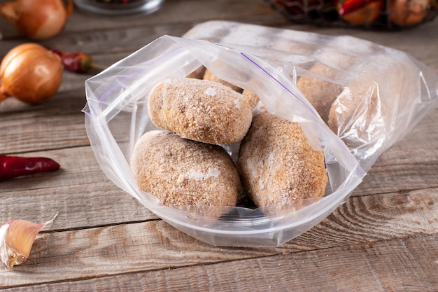 Plastic bags with frozen meat and cutlets in plastic bag on a wooden table