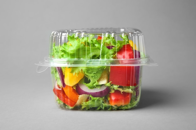 Plastic bak met salade op grijze achtergrond