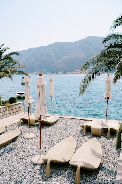 Plastic beach loungers on a pebble beach kotor bay in montenegro the city of dobrota under the