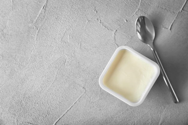 Plastic beker met lekkere yoghurt op grijze achtergrond bovenaanzicht