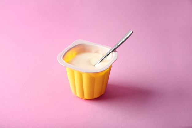 Plastic beker met lekkere yoghurt op kleur achtergrond