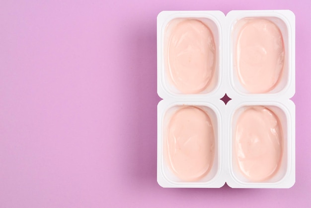 Plastic beker met lekkere yoghurt op lila achtergrond Bovenaanzicht Ruimte voor tekst of ontwerp