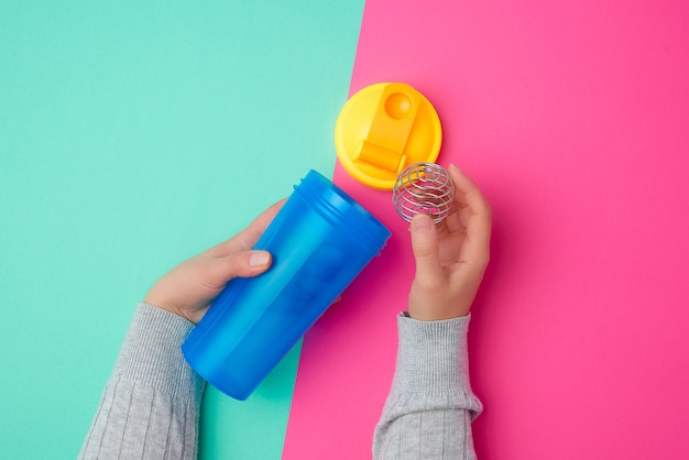 Plastic blauwe schudfles met een gele dop en een ijzeren bal voor sportmensen