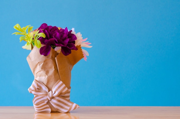 Foto plastic bloem in bruine zak op blauwe achtergrond