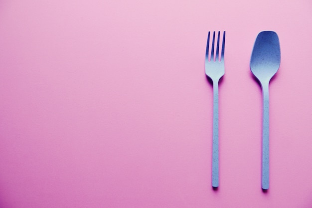 Plastic Blue Spoon and Fork On Pink Background