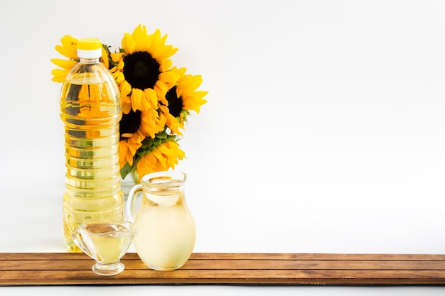 Plastic bottle and glass jars with sunflower oil and bouquet on wood