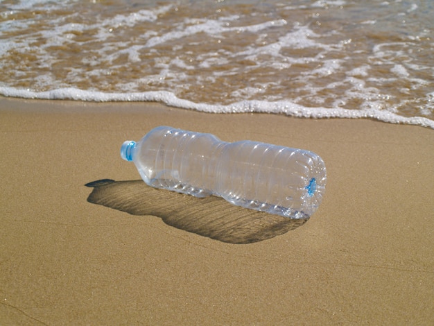 Plastic bottle on the sand at the beach, reduce, reuse and recycle plastic