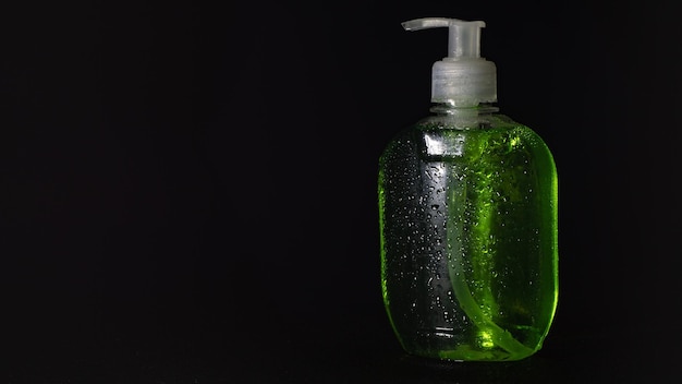 plastic bottle for soap with dispenser in drops of water on a black background