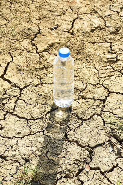 Foto bottiglia d'acqua di plastica sul soi incrinato