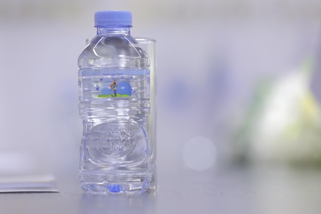 Пластиковая бутылка воды на столе в офисе с размытым фоном