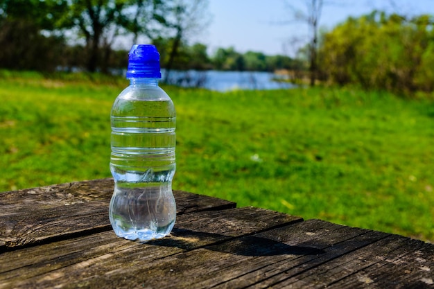 素朴な木製のテーブルに澄んだ水とプラスチックボトル