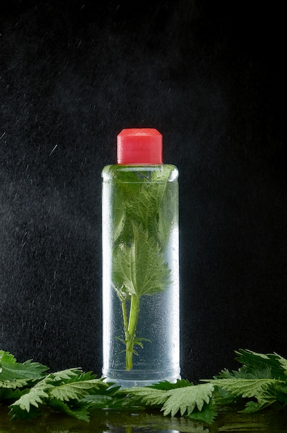 Plastic bottle with fresh nettle in clouds of water dust