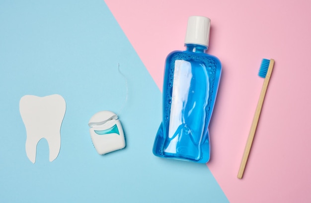 Foto bottiglia di plastica con collutorio, spazzolino da denti in legno su sfondo blu