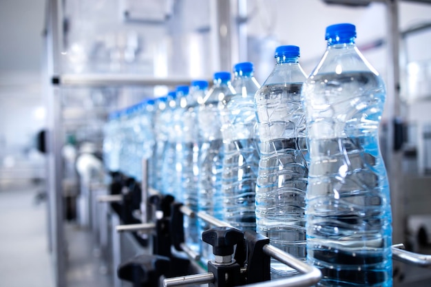 Plastic bottles on conveyor belt being filled with drinking water