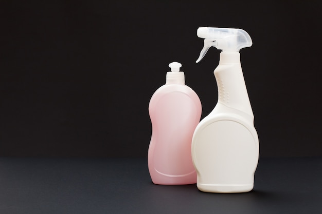 Plastic bottles of dishwashing liquid on the black background. Washing and cleaning set.