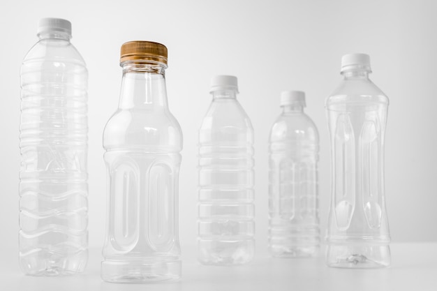 Plastic bottles in various shapes and sizes on white table and background