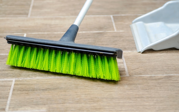 Plastic broomstick green fibers cleaning the floor. Household hygiene and sweeping dust