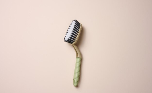 Plastic brush with handle for cleaning the house on beige background, top view