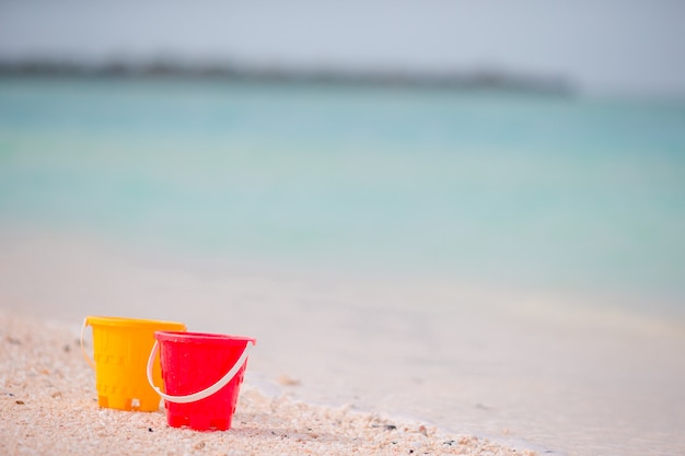 Plastic buckets on the white sandy beach, seashore