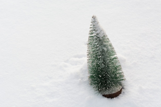 Plastic christmas tree on real snow with copy space winter holiday background