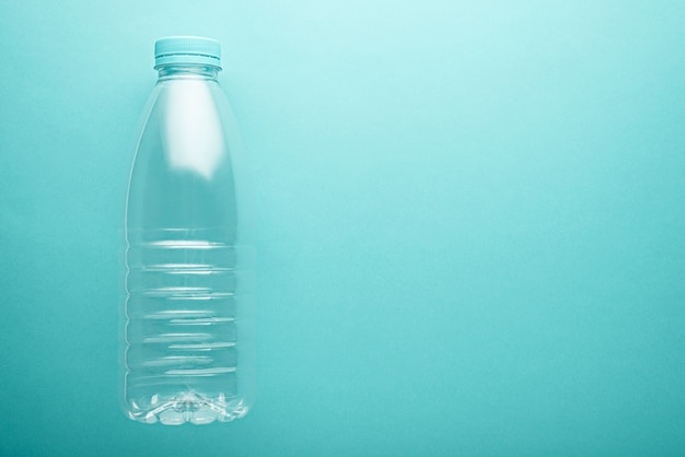 Plastic clean water bottle with blue cover with copy space on neo mint background. environmental pollution concept