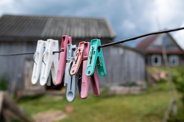 Plastic clothespins hang on clotheslines in a rustic courtyard against of a wooden barn and the sky