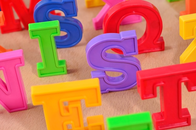 Plastic colorful alphabet letters close up on a wooden background