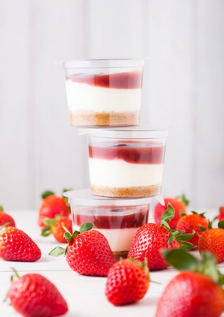 Plastic container met aardbeiroom dessert op houten tafel met verse aardbeien