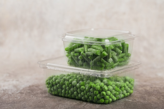 Plastic container with different organic deep frozen vegetables on a table