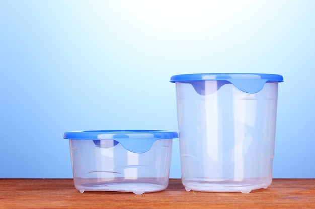 Plastic containers for food on wooden table on blue background