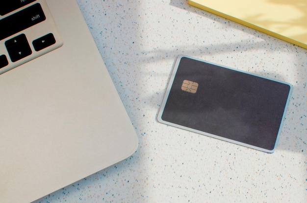 Plastic credit card with chip visible on top of a table with soft lights and shadows on the surface.