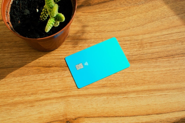Plastic credit card with chip visible on top of a table with\
soft lights and shadows on the surface.