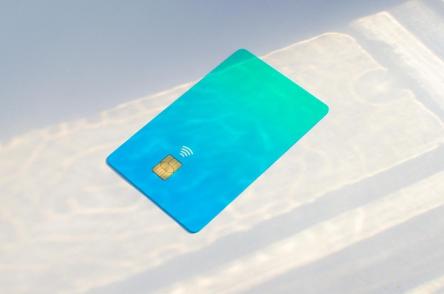 Photo plastic credit card with chip visible on top of a table with soft lights and shadows on the surface.