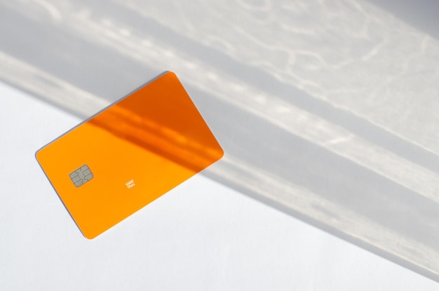 Plastic creditcard met chip zichtbaar bovenop een tafel met zachte lichten en schaduwen op het oppervlak.