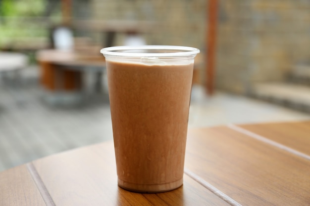 Plastic cup of delicious cool drink on wooden table