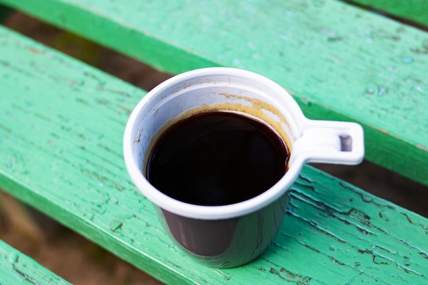 Plastic cup with coffee on a wooden bench